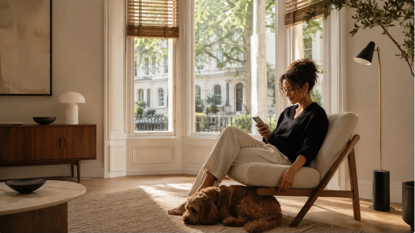 A woman sitting calmly with her dog in a light-filled London living room